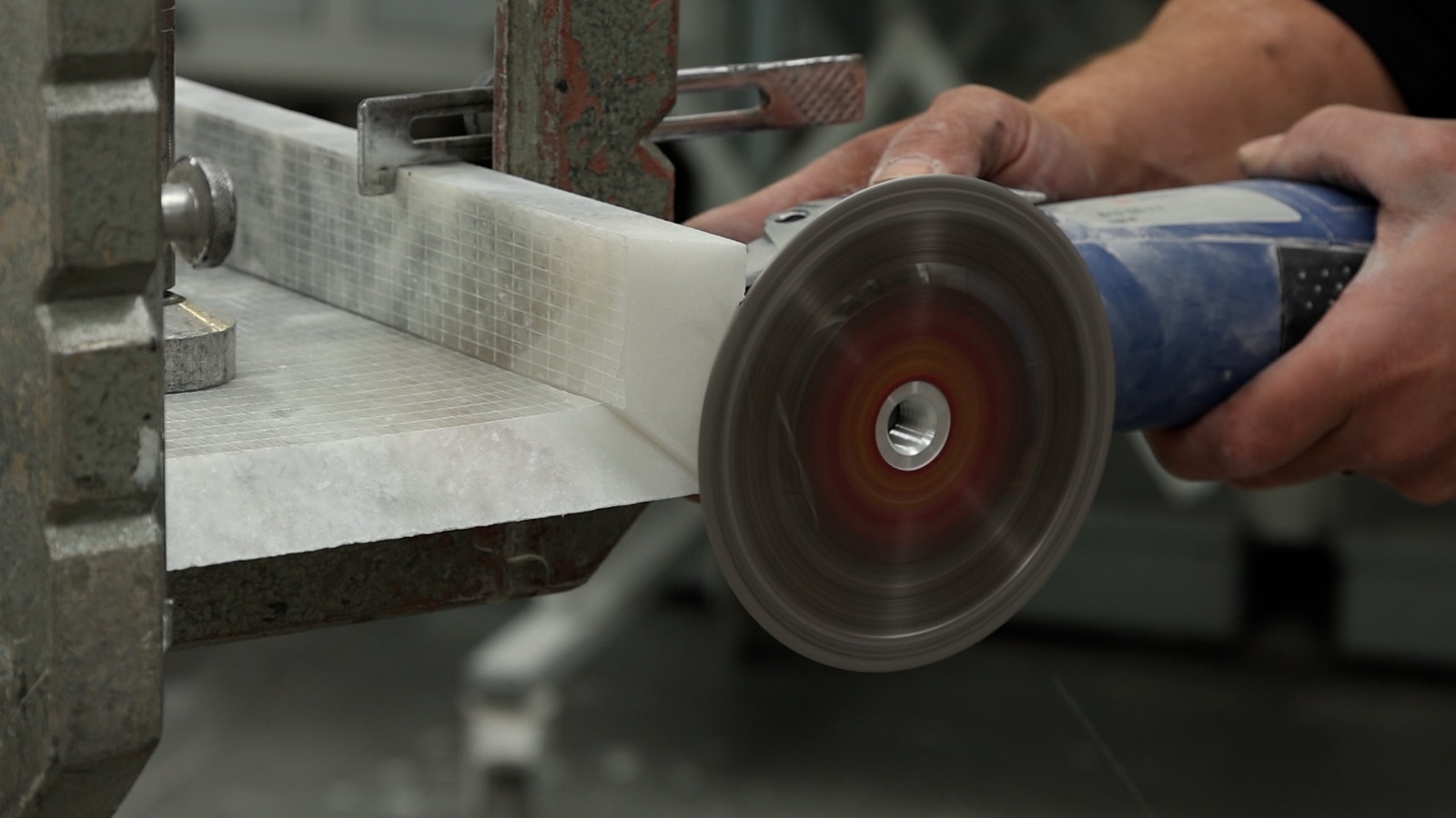 Een natuurstenen plaat wordt in het atelier met een slijpschijf bewerkt