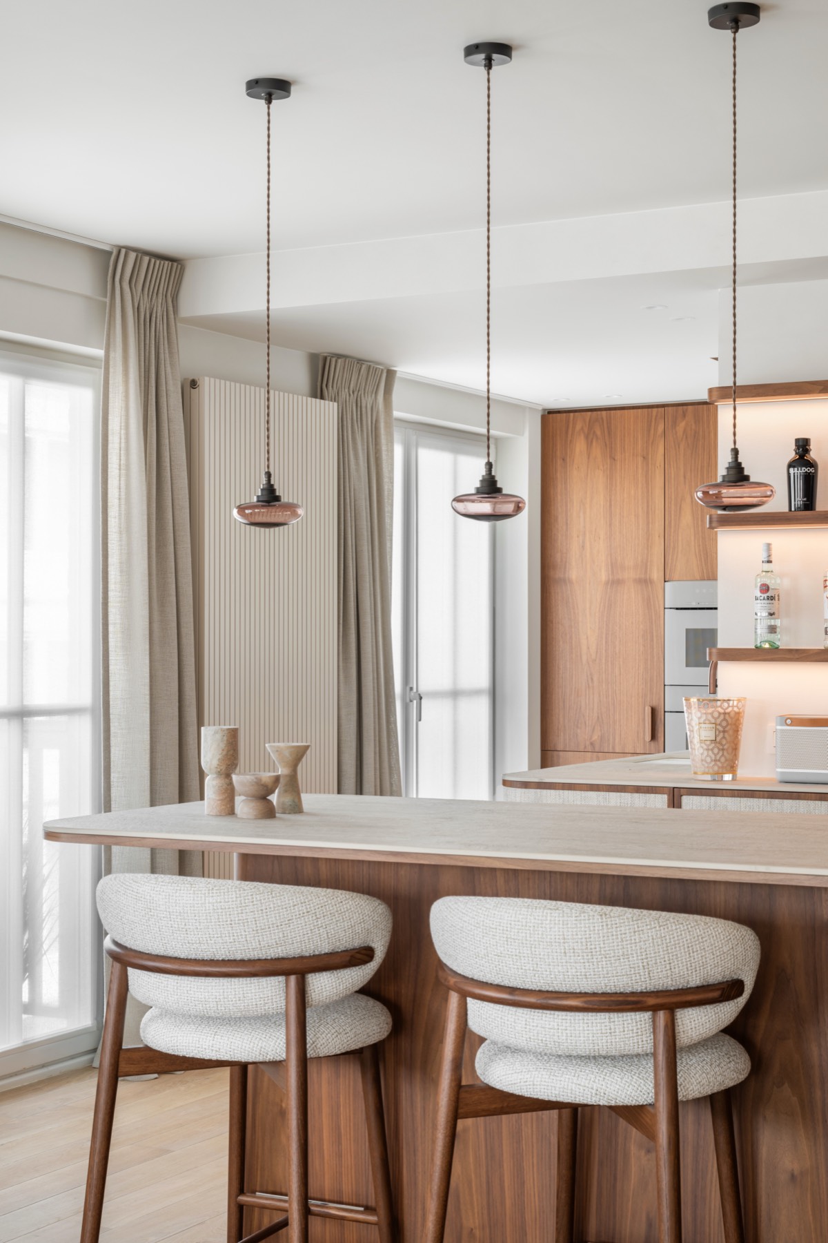 Keuken met een licht werkblad op een houten eiland, barkrukken en hanglampen