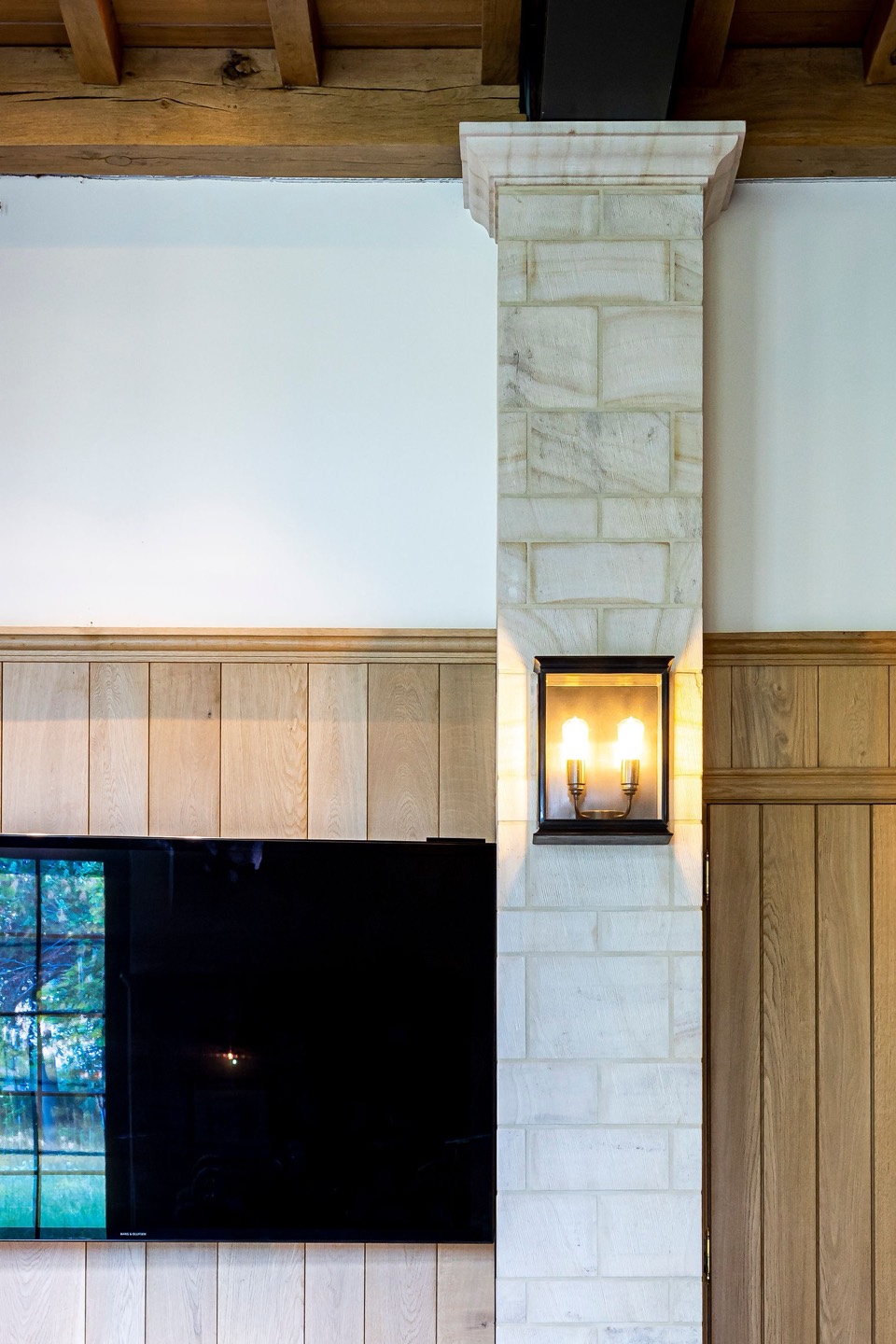 Natuurstenen zuil met wandlamp tussen houten lambrisering