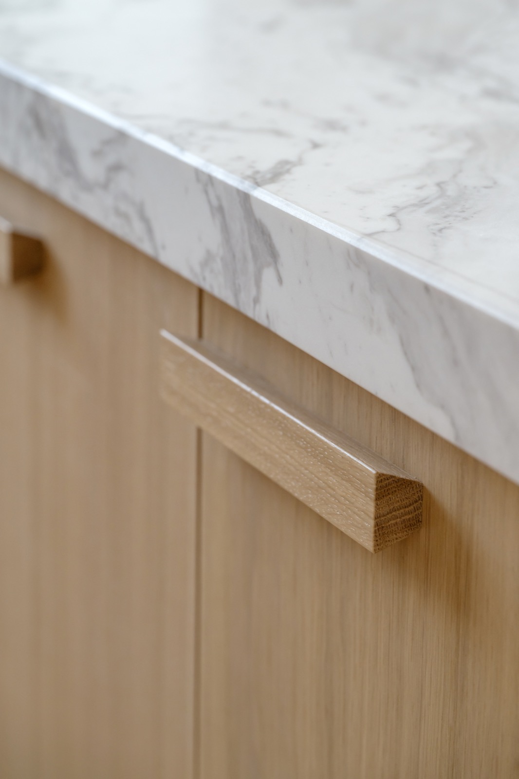 Detail van een wit marmeren werkblad op houten keukenkasten