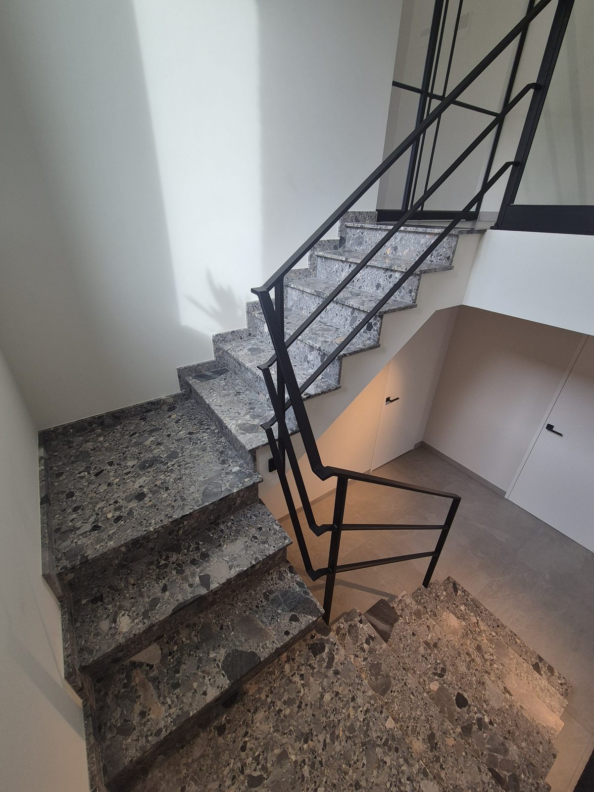 Trap met bordes in terrazzo en een zwarte metalen leuning